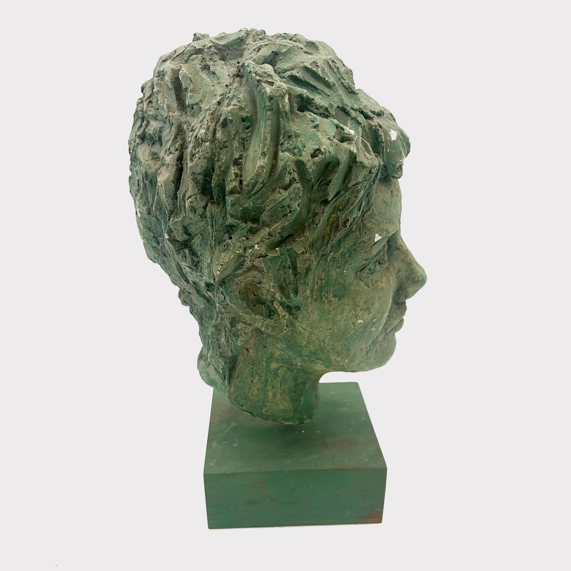 side view of roman head plaster bust on a mount with virdigris finish