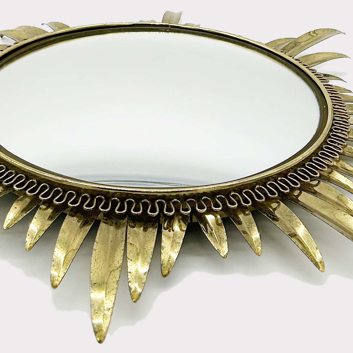 close up side view of Convex Mirror framed by starburst brass pattern