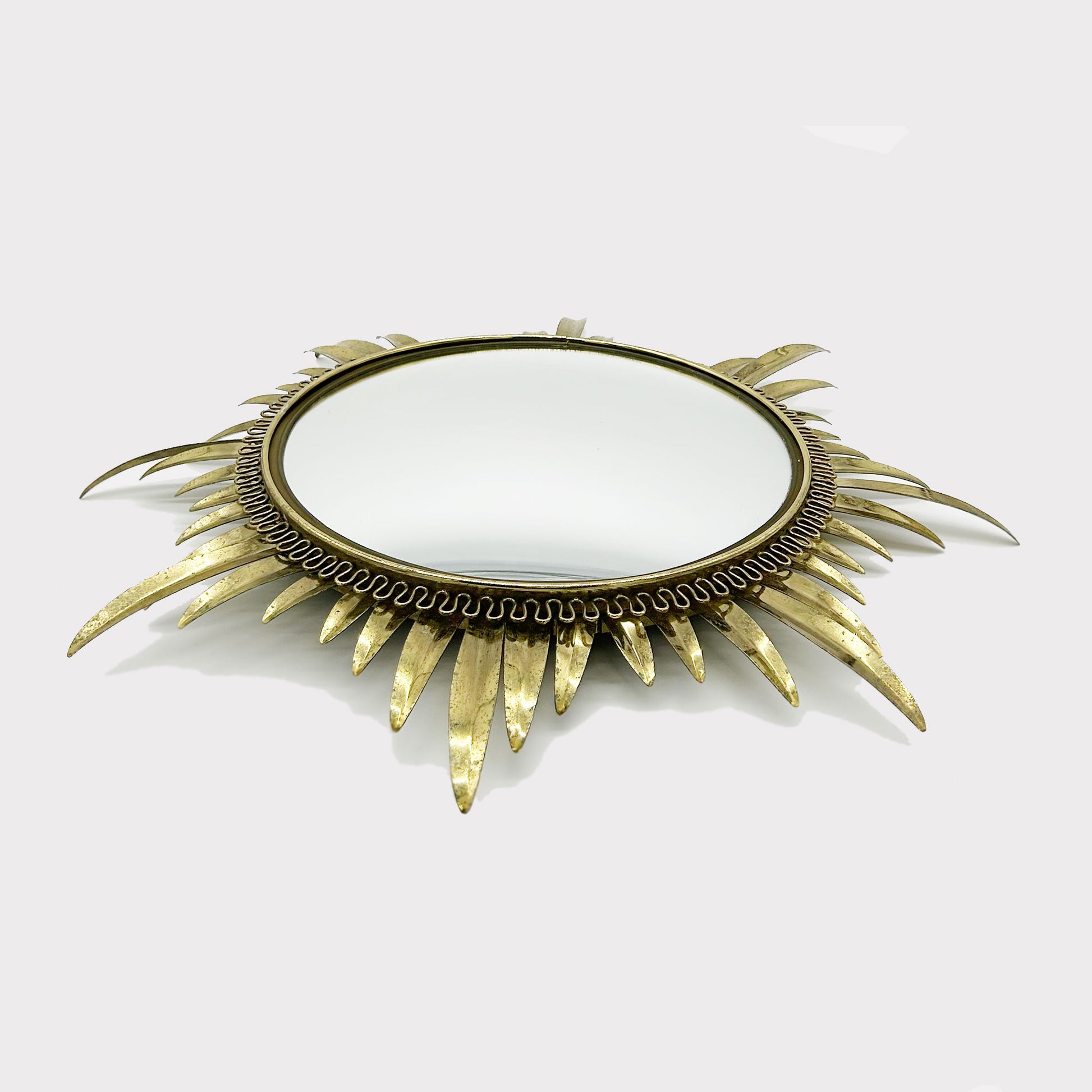 side view of Convex Mirror framed by starburst brass pattern